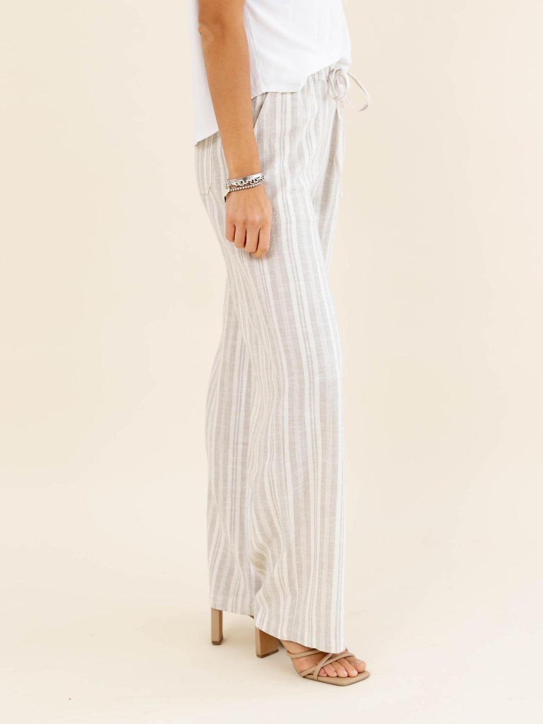 Person wearing white striped pants on a beige background