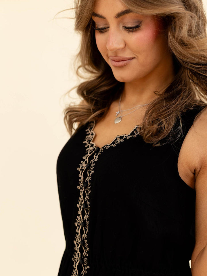 Woman wearing a black dress with intricate detailing on a beige background