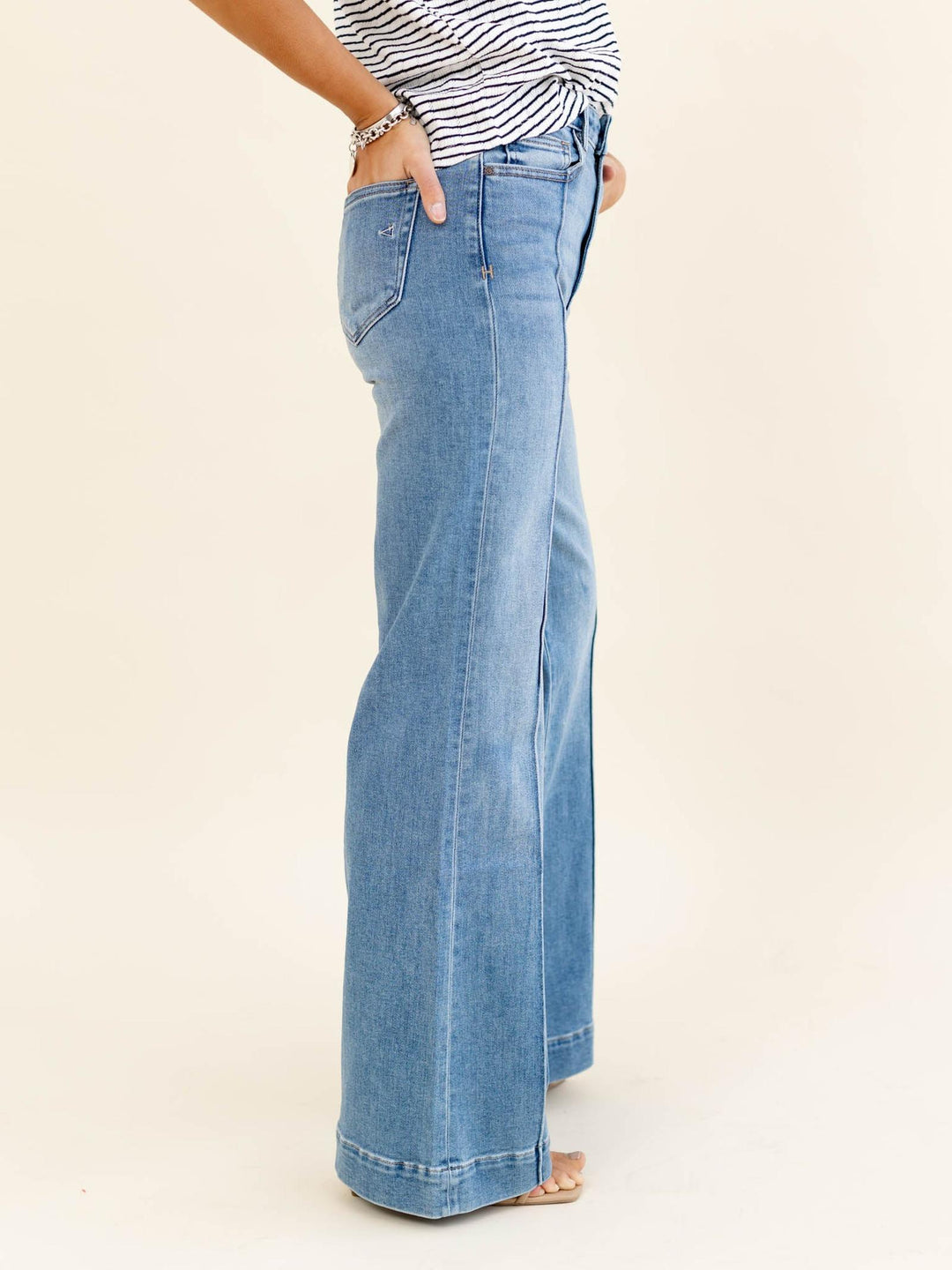 Person wearing light blue wide-leg jeans on a beige background