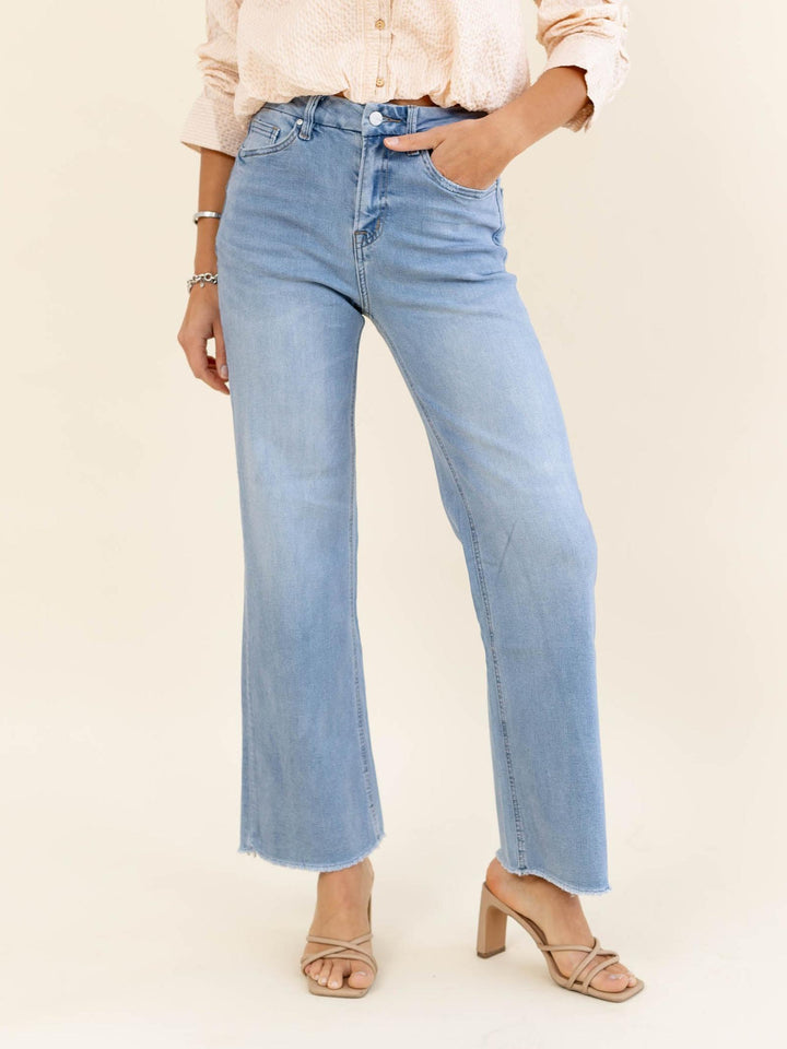 Light blue jeans worn by a person on a beige background