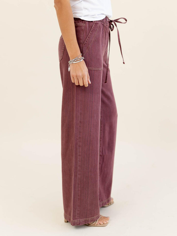 Person wearing maroon wide-leg pants with a white background