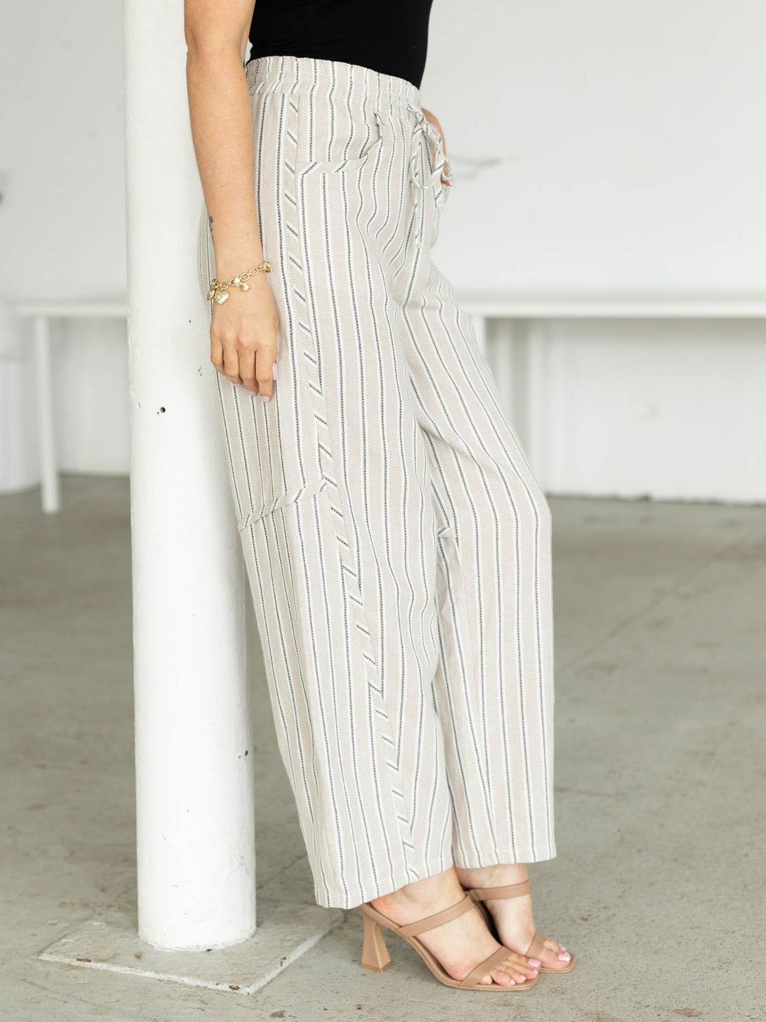 Person wearing white pinstripe pants in a minimal indoor setting