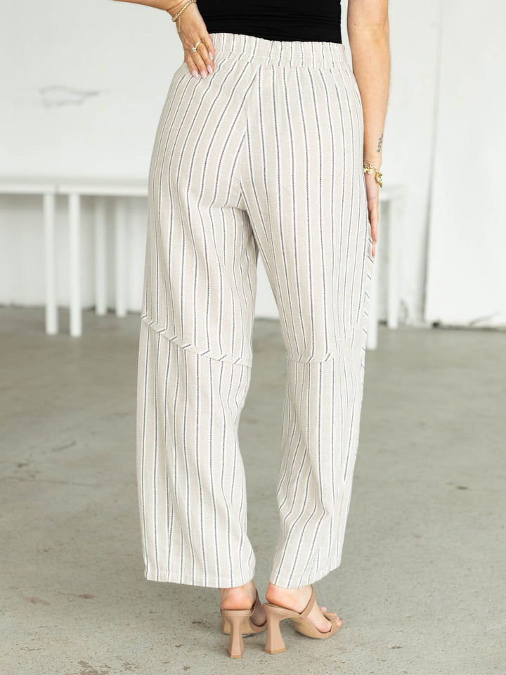 Person wearing white pinstripe pants in a minimal indoor setting