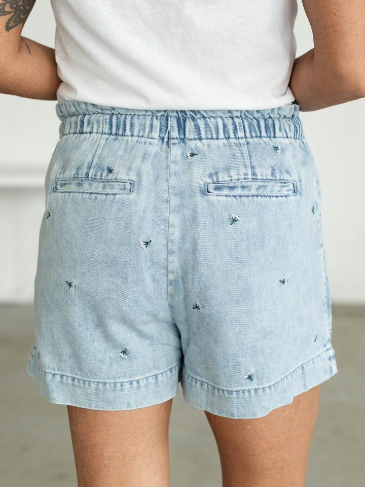 Light blue denim shorts with rhinestone embellishments worn by a person.