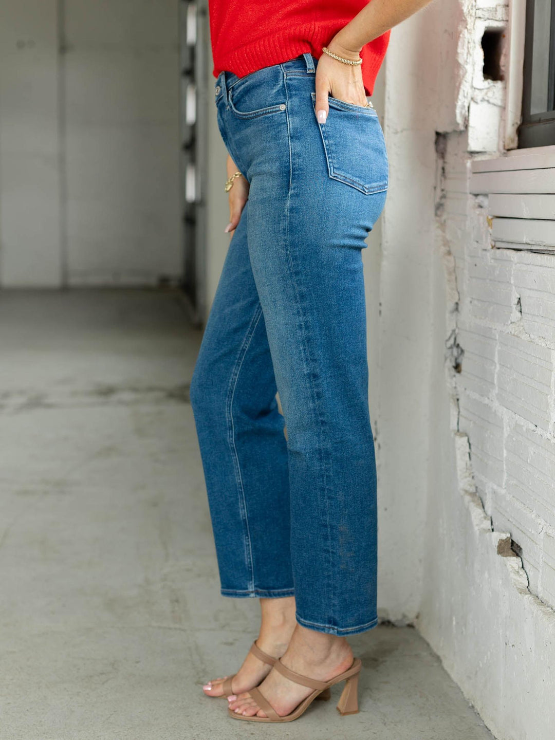 Person wearing blue jeans and a red top in an urban setting.