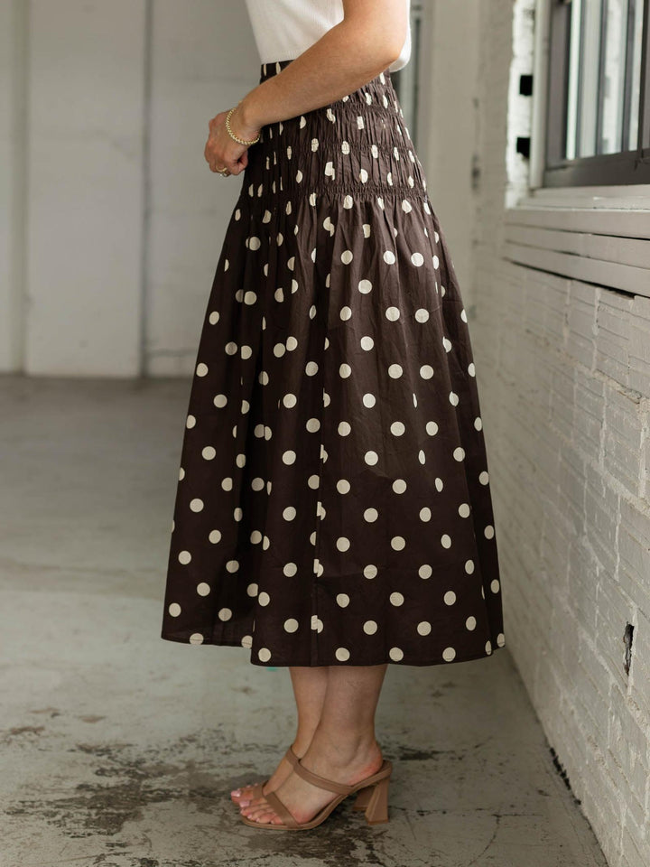 Person wearing a brown polka dot skirt in an urban setting