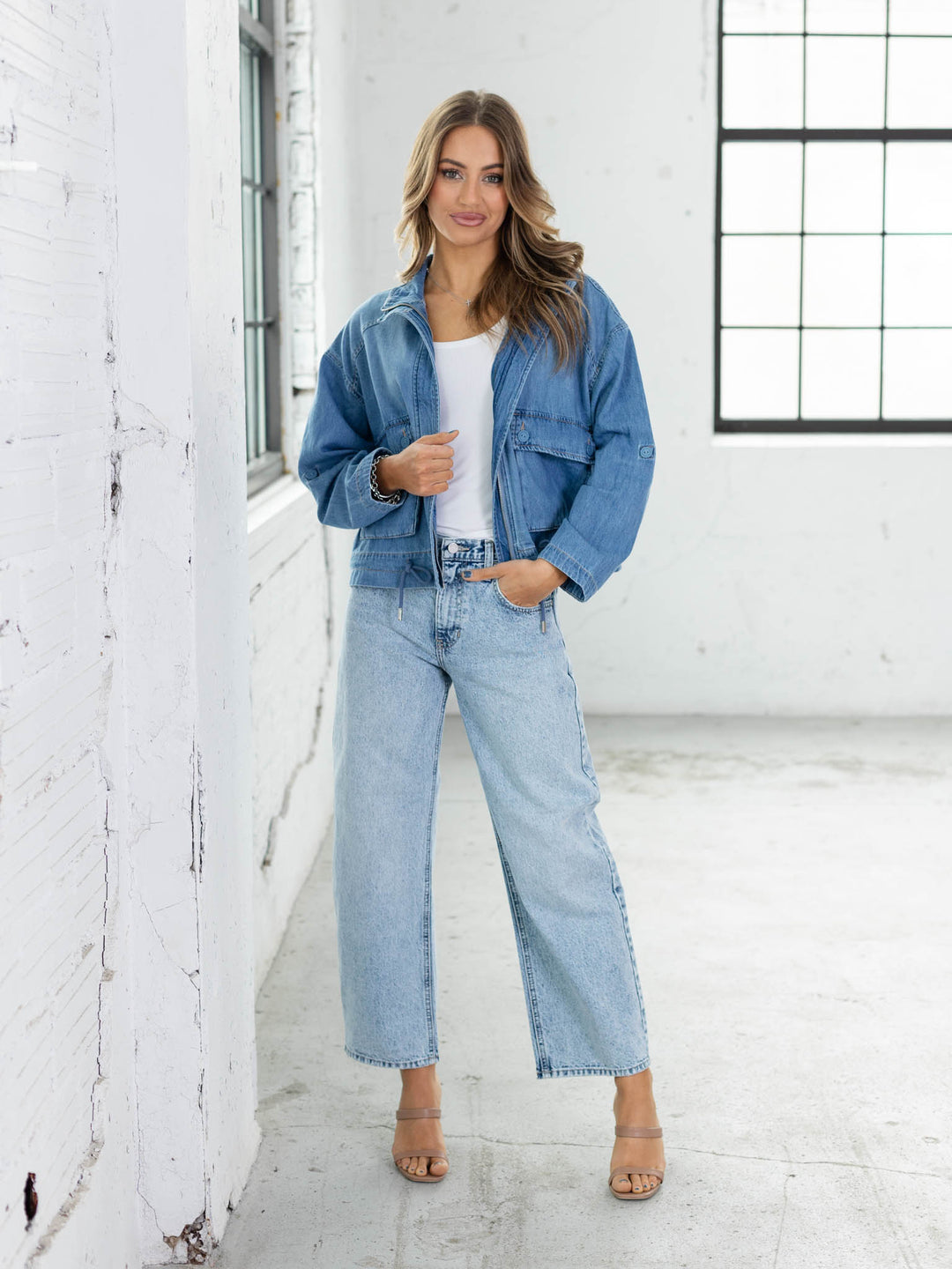 Woman wearing a denim jacket and jeans in a white room