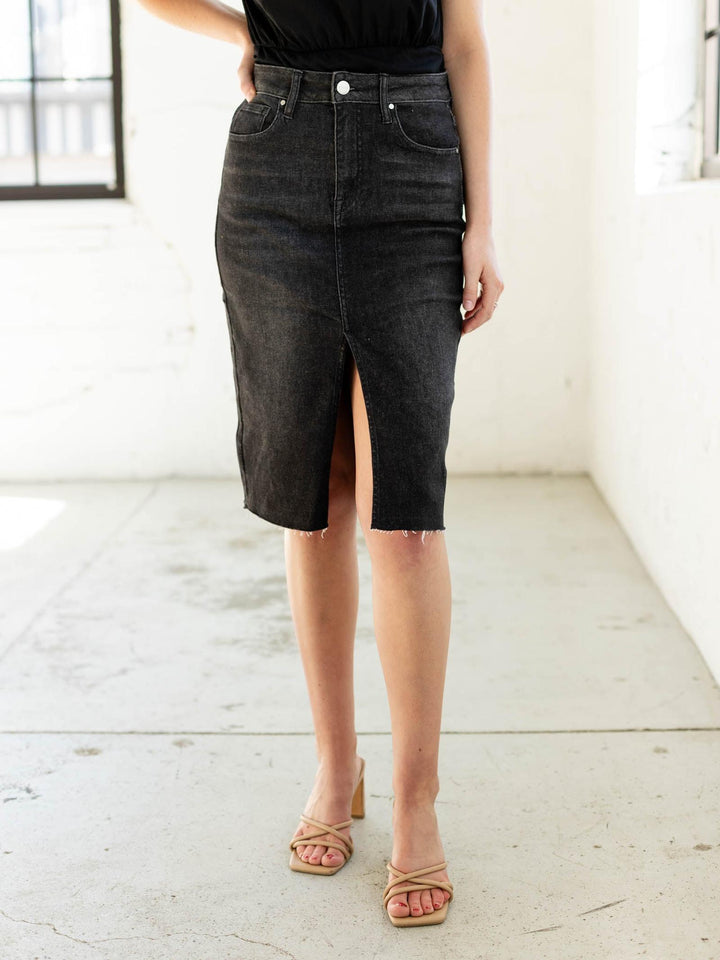 Person wearing a black denim skirt with a white background