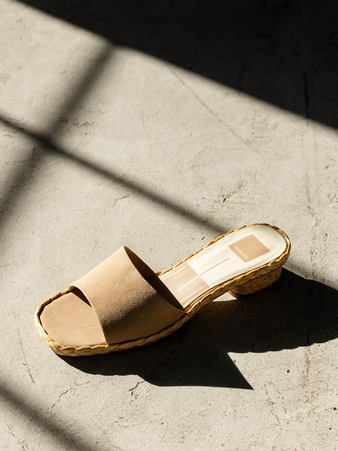 Beige sandal on a concrete surface with shadows