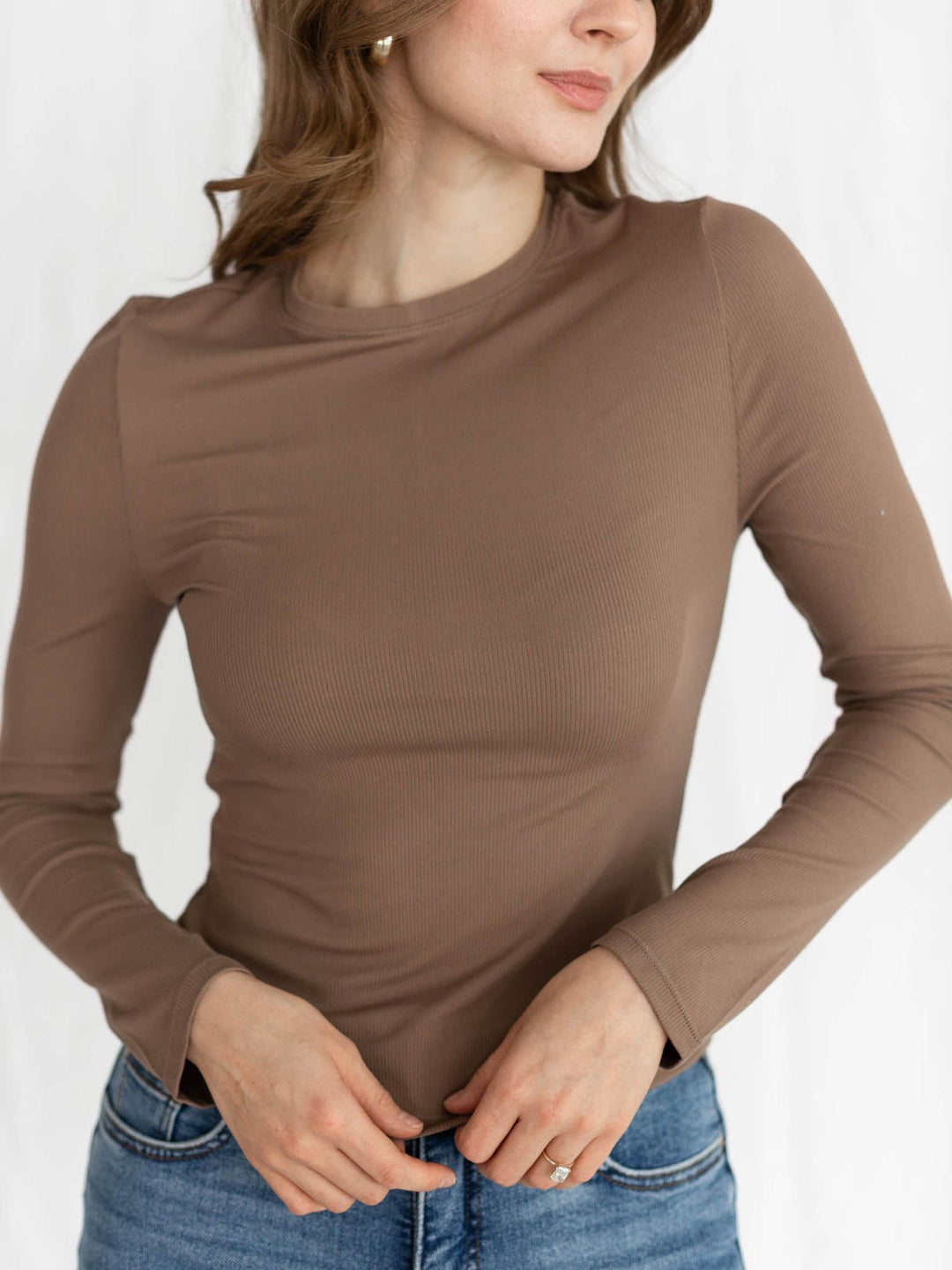 Woman wearing a brown long-sleeve top against a white background