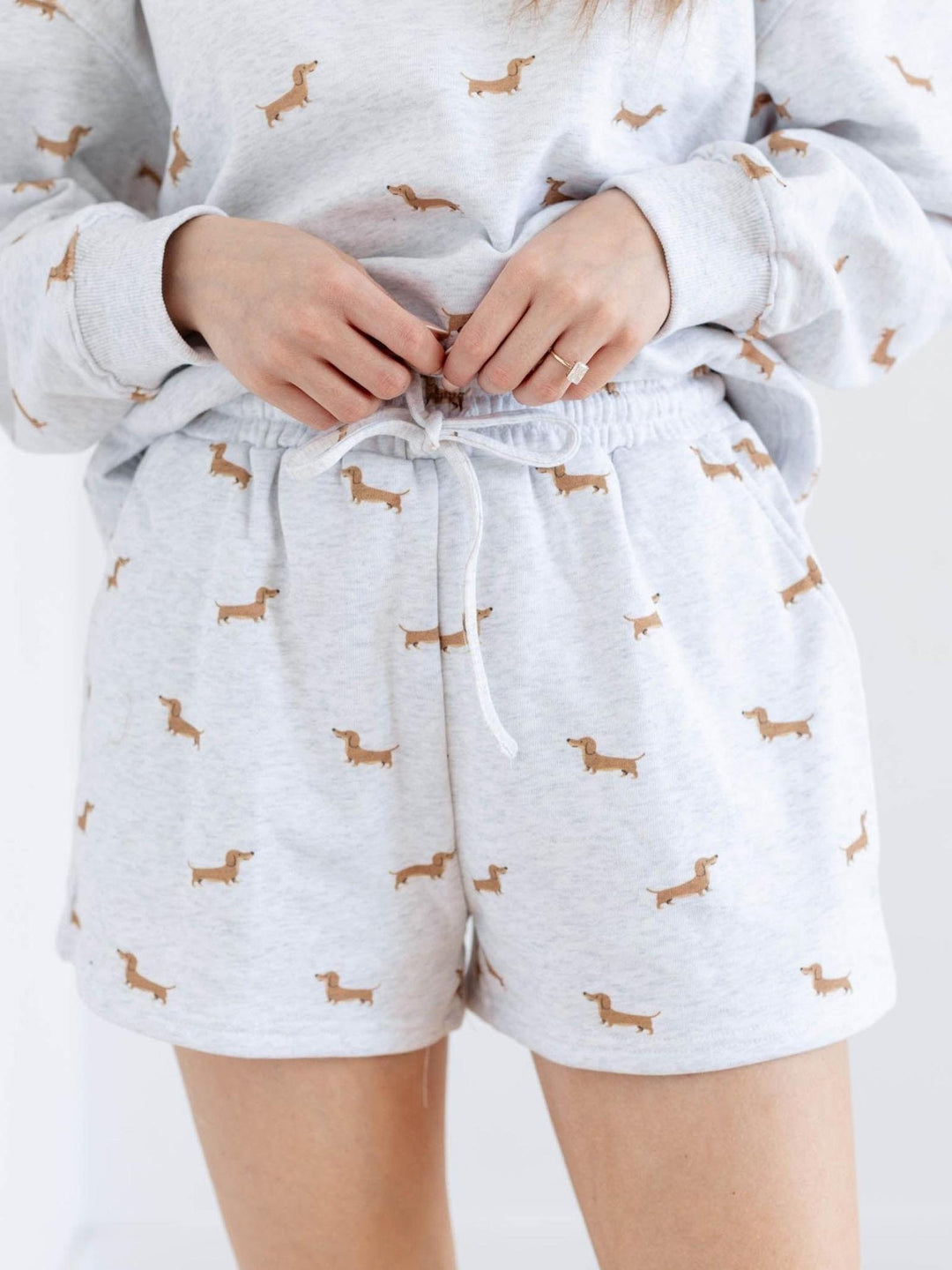 Person wearing a light gray pajama set with dachshund patterns on a white background
