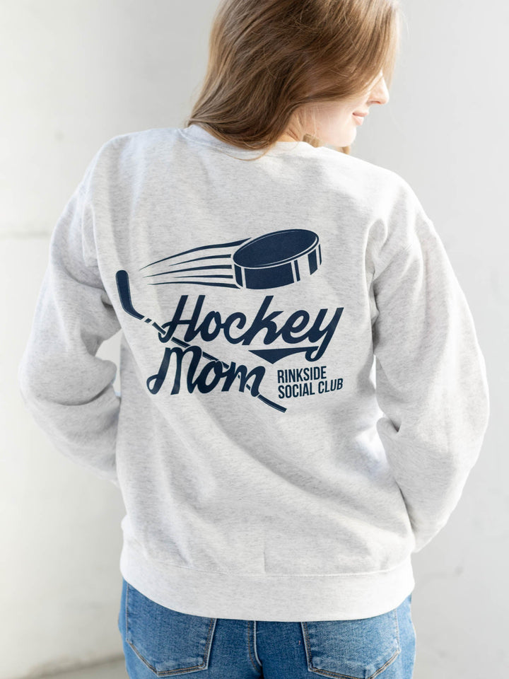 Person wearing a gray sweatshirt with 'Hockey Mom' and 'Rinkside Social Club' text on the back.