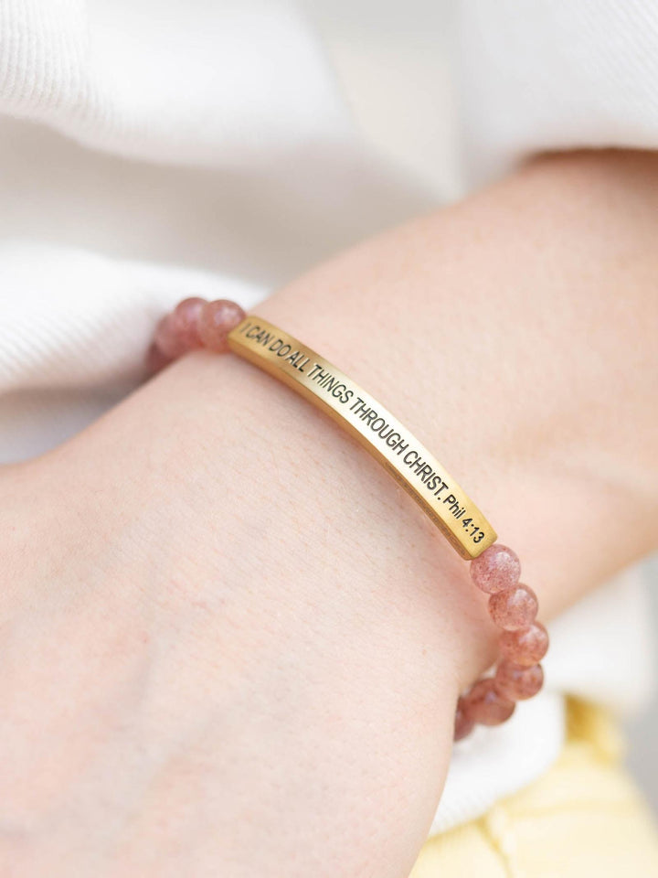 Pink Quartz stone bracelet with a gold bar engraved "I CAN DO ALL THINGS THROUGH CHRIST. Phil 4:13" on a wrist.