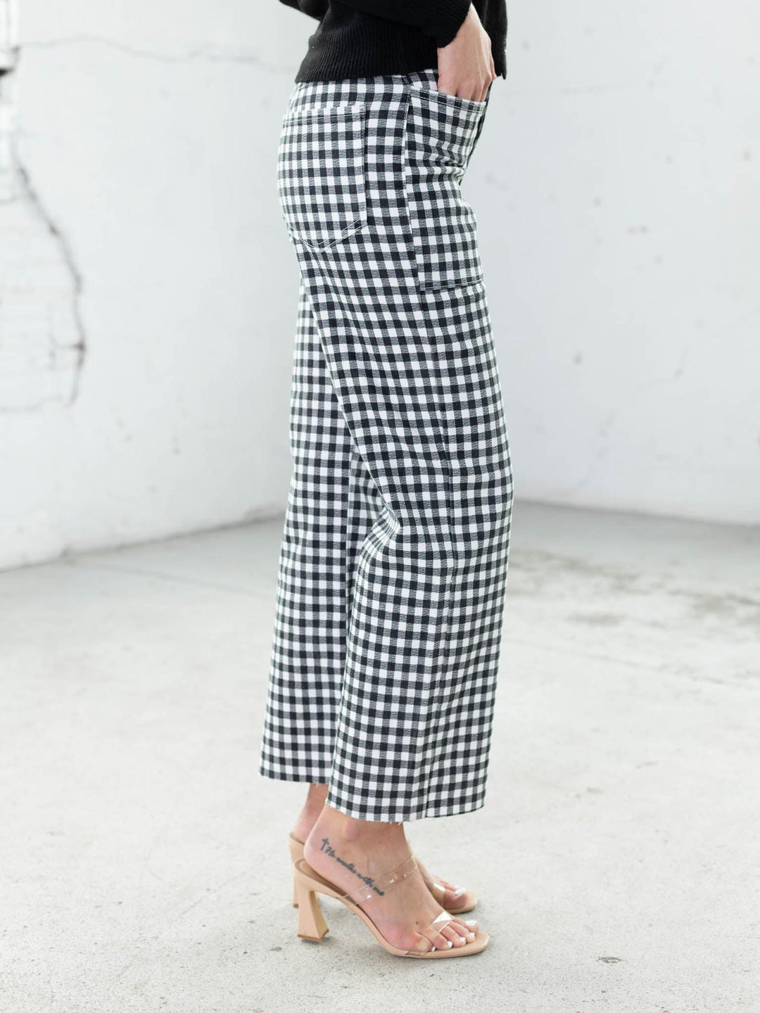 Person wearing black and white checkered pants on a light background