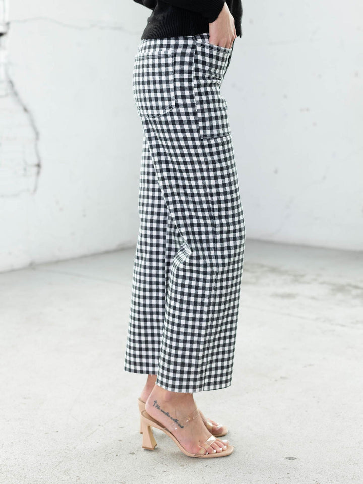 Person wearing black and white checkered pants on a light background