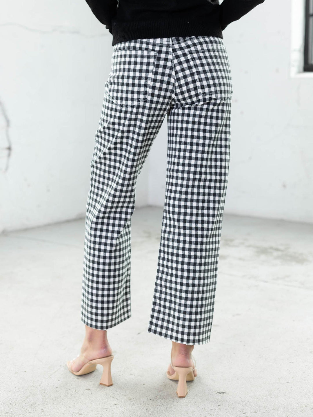 Person wearing black and white checkered pants against a white background