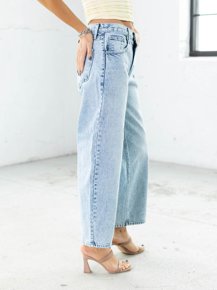 Light blue jeans worn by a person on a white floor with a white wall background