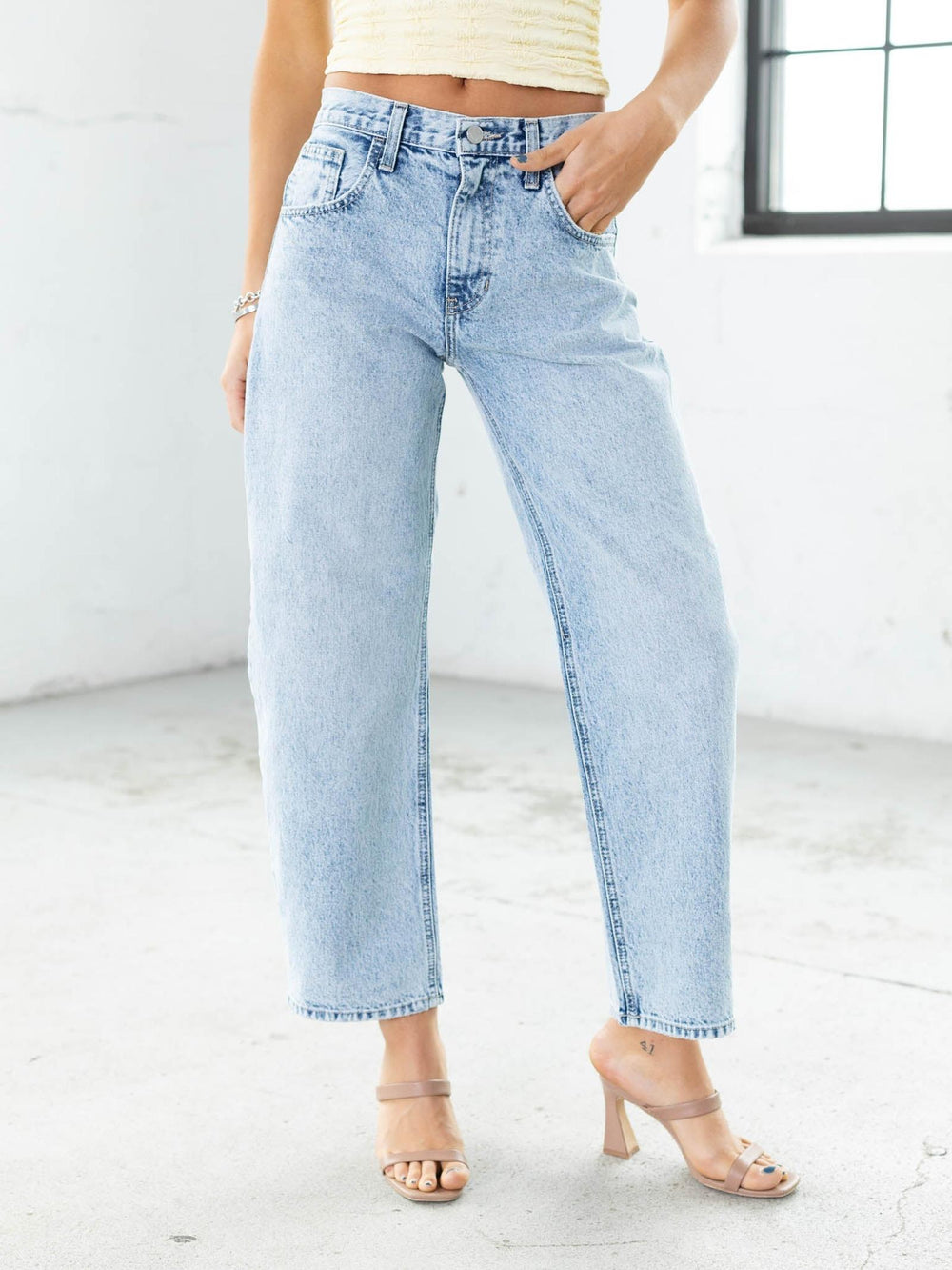 Light blue jeans worn by a person on a white floor with a neutral background