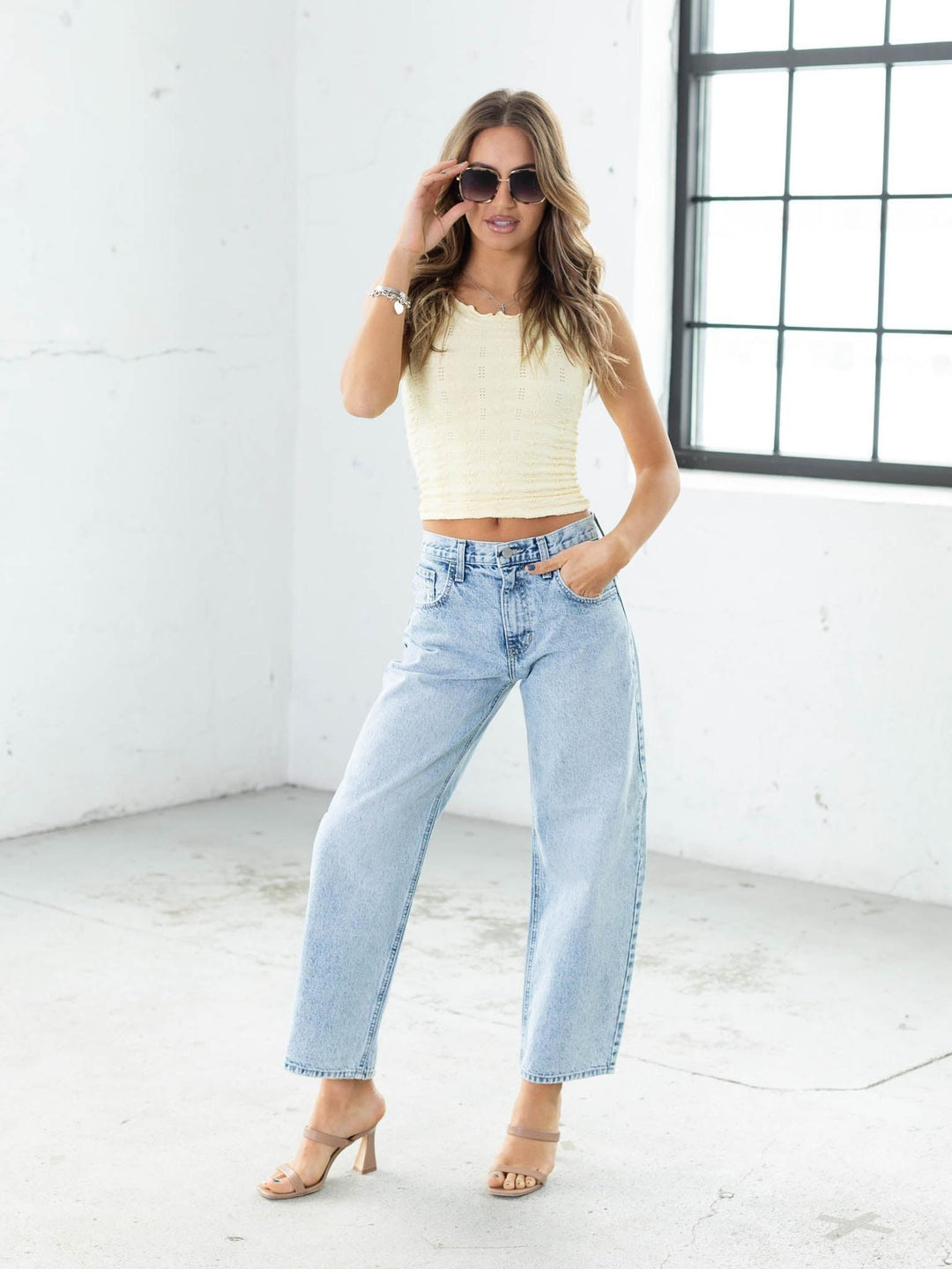 Woman wearing a cream top and light blue jeans in a bright room.