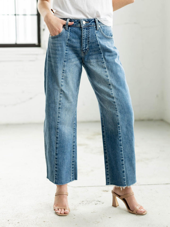 Woman wearing a white t-shirt and blue jeans standing in a minimalistic room.