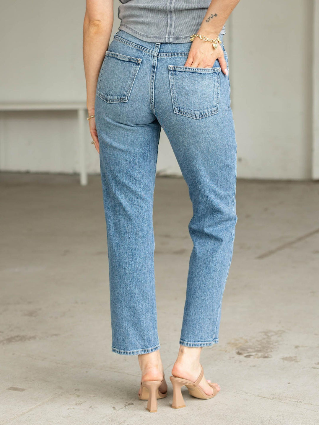 Person wearing light blue jeans standing in a minimal indoor setting