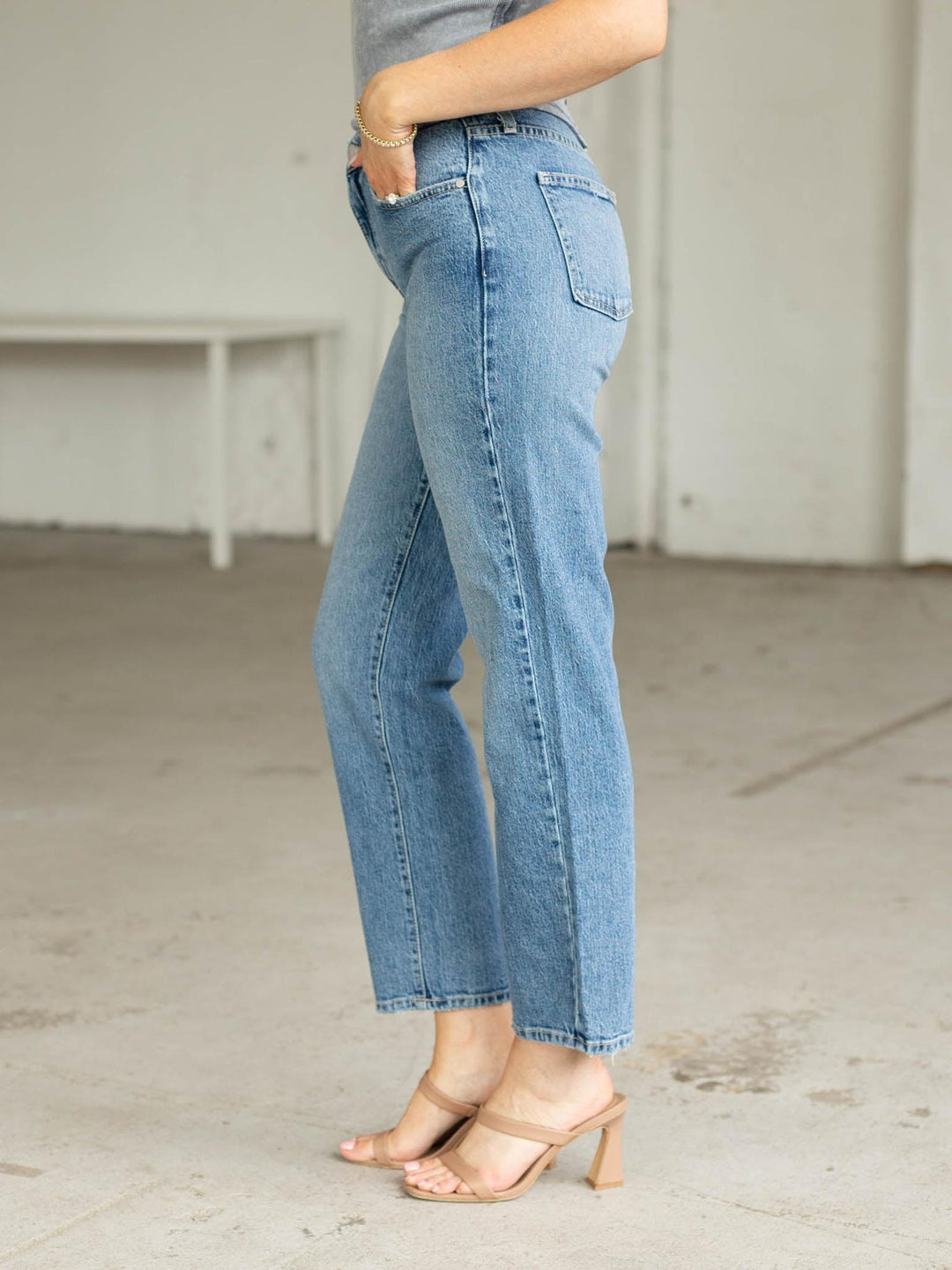 Person wearing light blue jeans in a minimal indoor setting