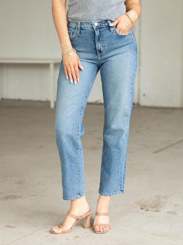 Person wearing light blue jeans and a gray top in an indoor setting