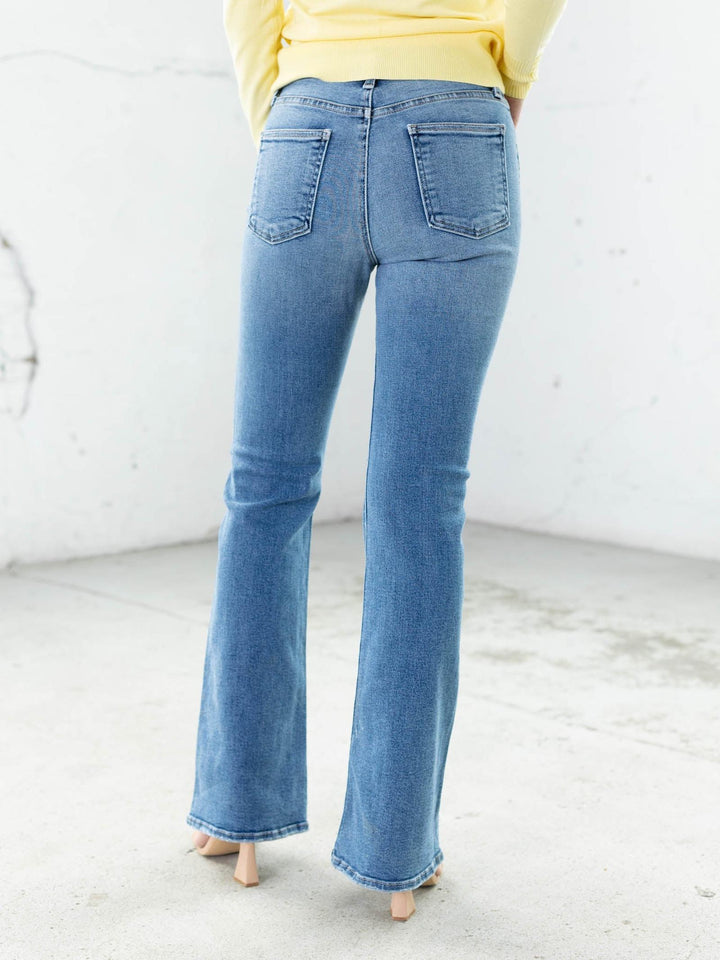 Person wearing light blue jeans and a yellow top on a white background