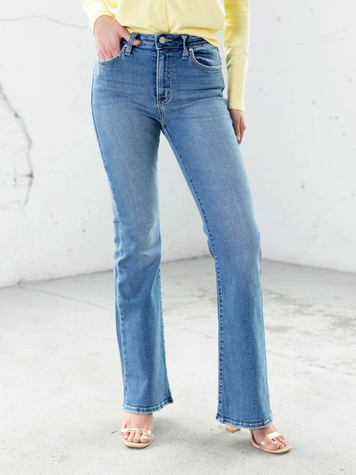 Person wearing blue jeans and a yellow top against a white background