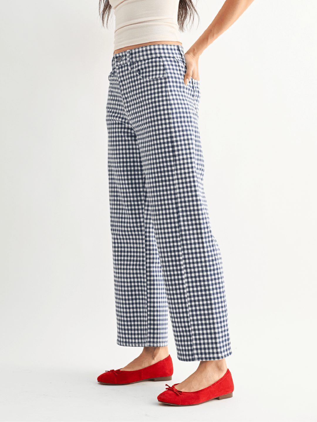 Person wearing blue and white checkered pants with red shoes on a white background
