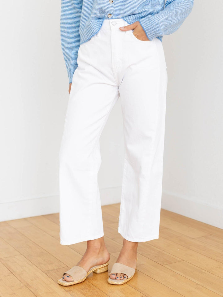 Person wearing white pants and a blue striped shirt on a wooden floor.