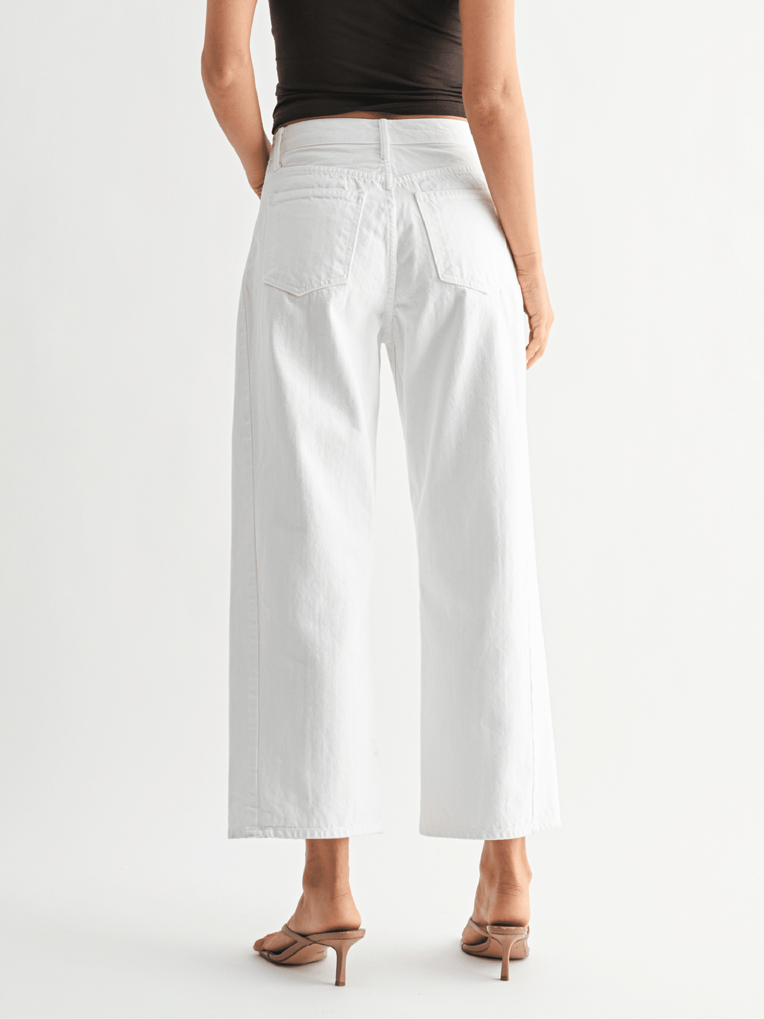 Person wearing white wide-leg pants on a white background