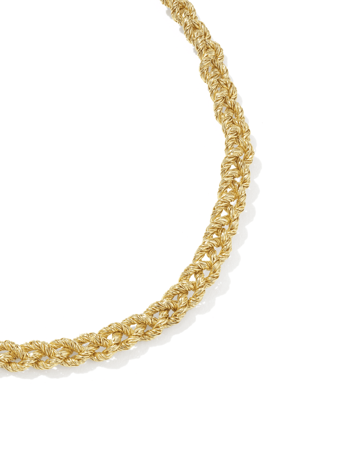 A close-up of a gold chain necklace with a textured, woven or braided link pattern, photographed on a clean white background.