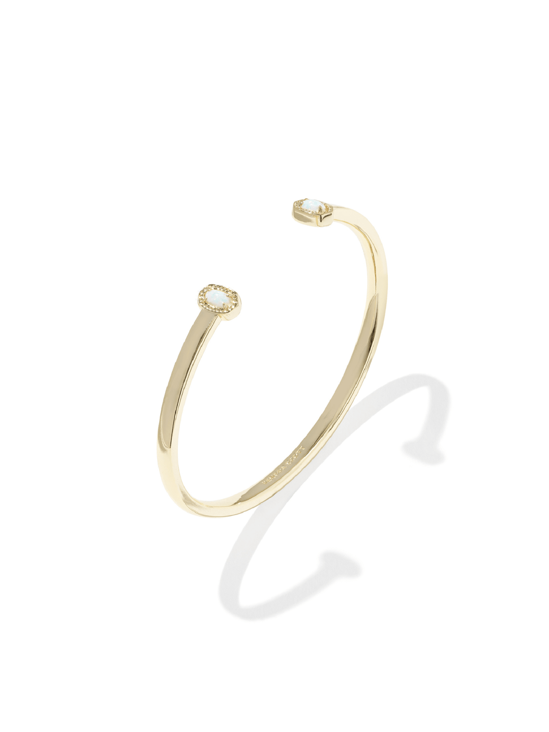 A slim gold cuff bangle bracelet with two small round clear gemstones, one at each end, displayed on a clean white background with a soft shadow.