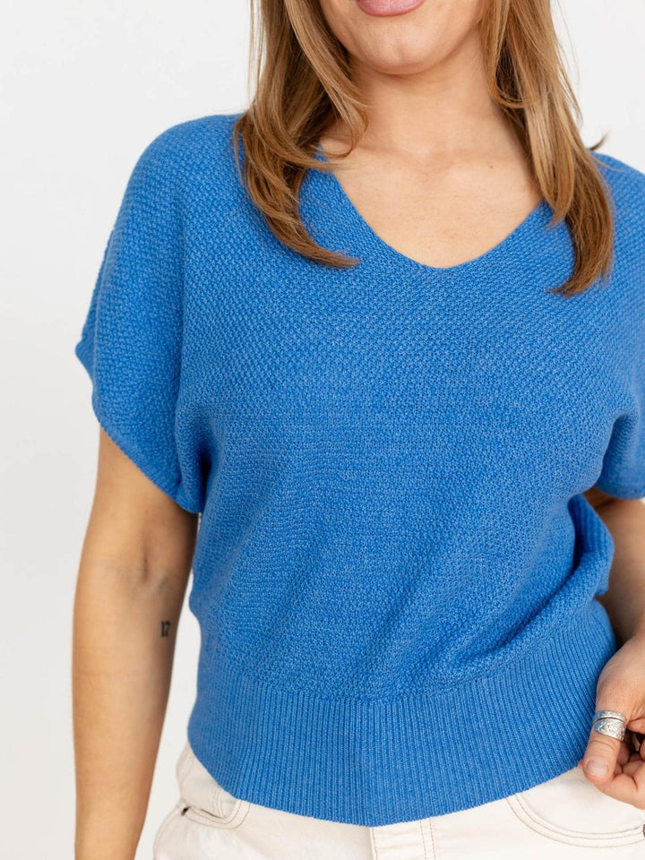 Blue knitted sweater worn by a person on a white background