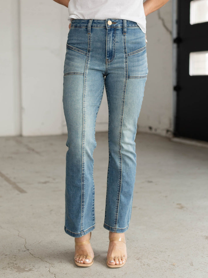 Person wearing blue jeans standing in a minimal indoor setting