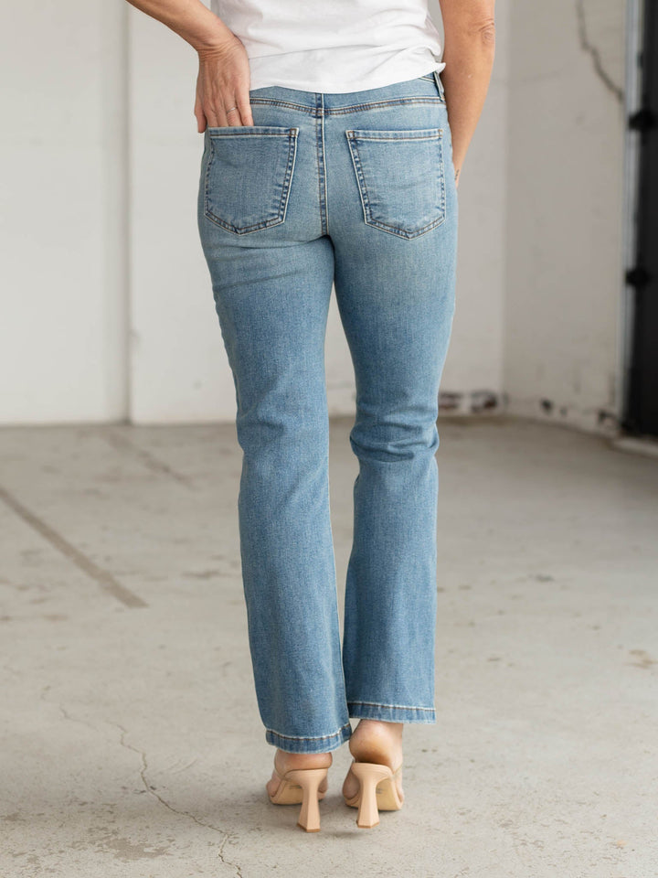 Person wearing light blue jeans and a white shirt in an indoor setting.