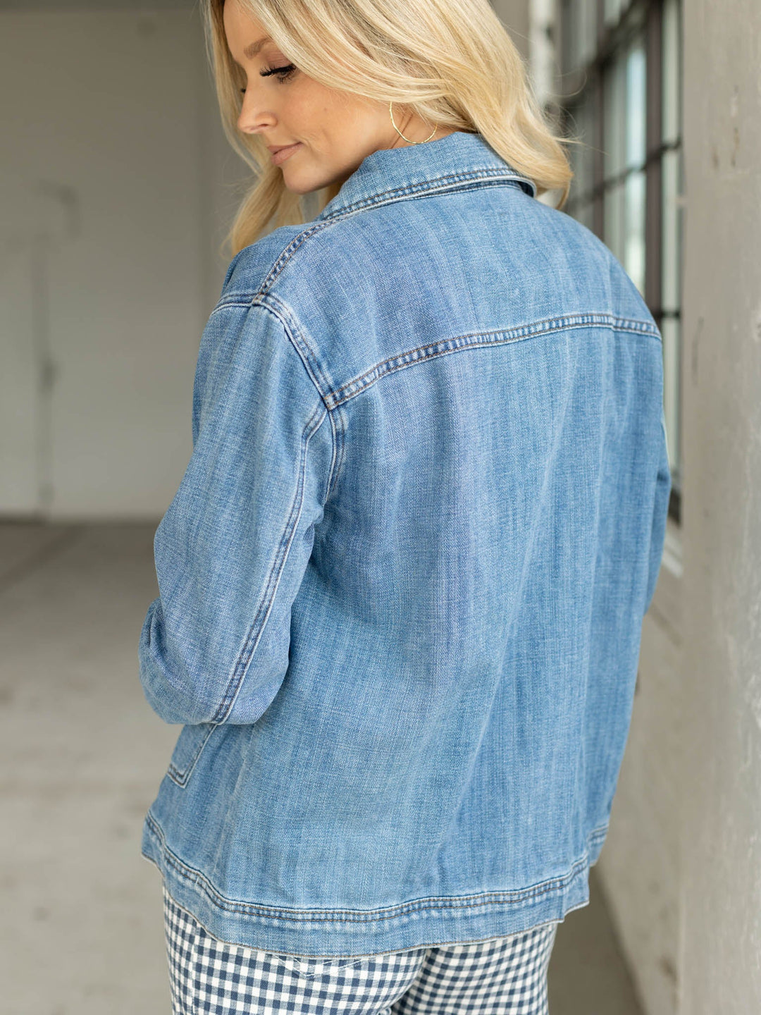 Woman wearing a light blue denim jacket in an indoor setting
