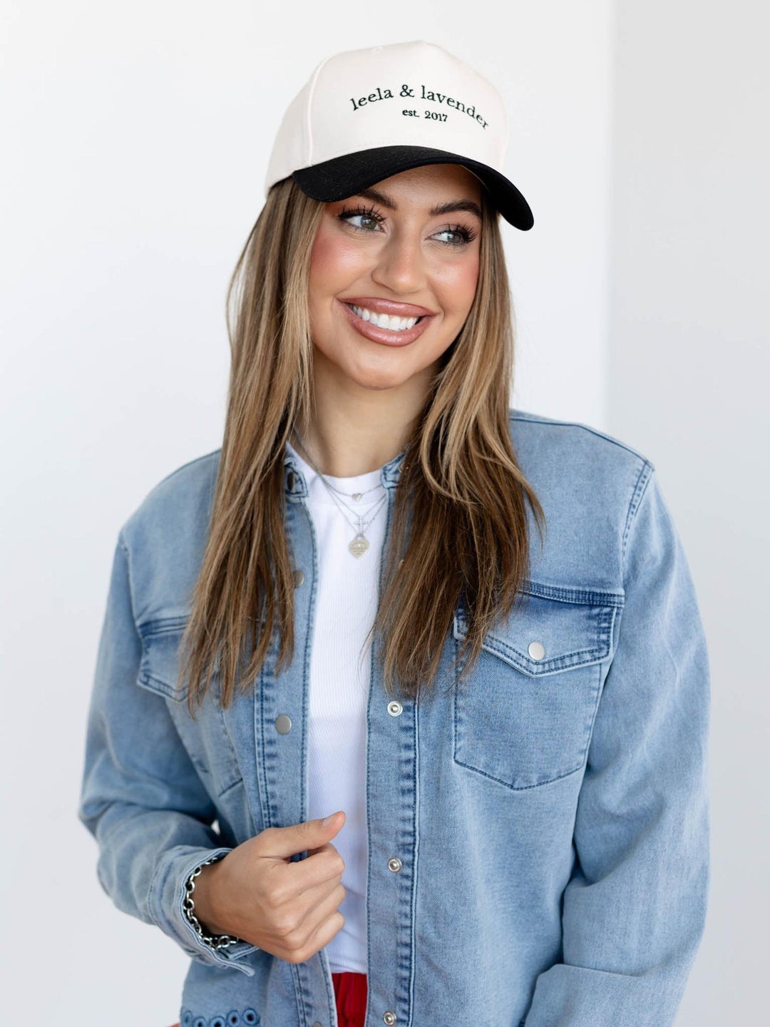 Woman wearing a denim jacket and a cap with &