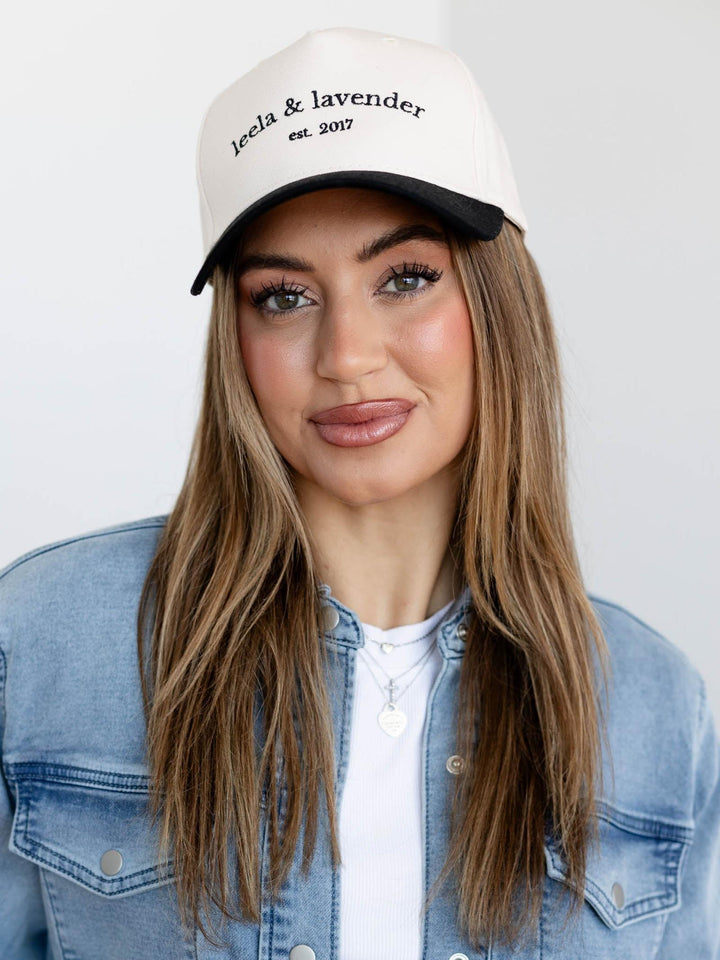 Woman wearing a white cap with text, standing against a plain background