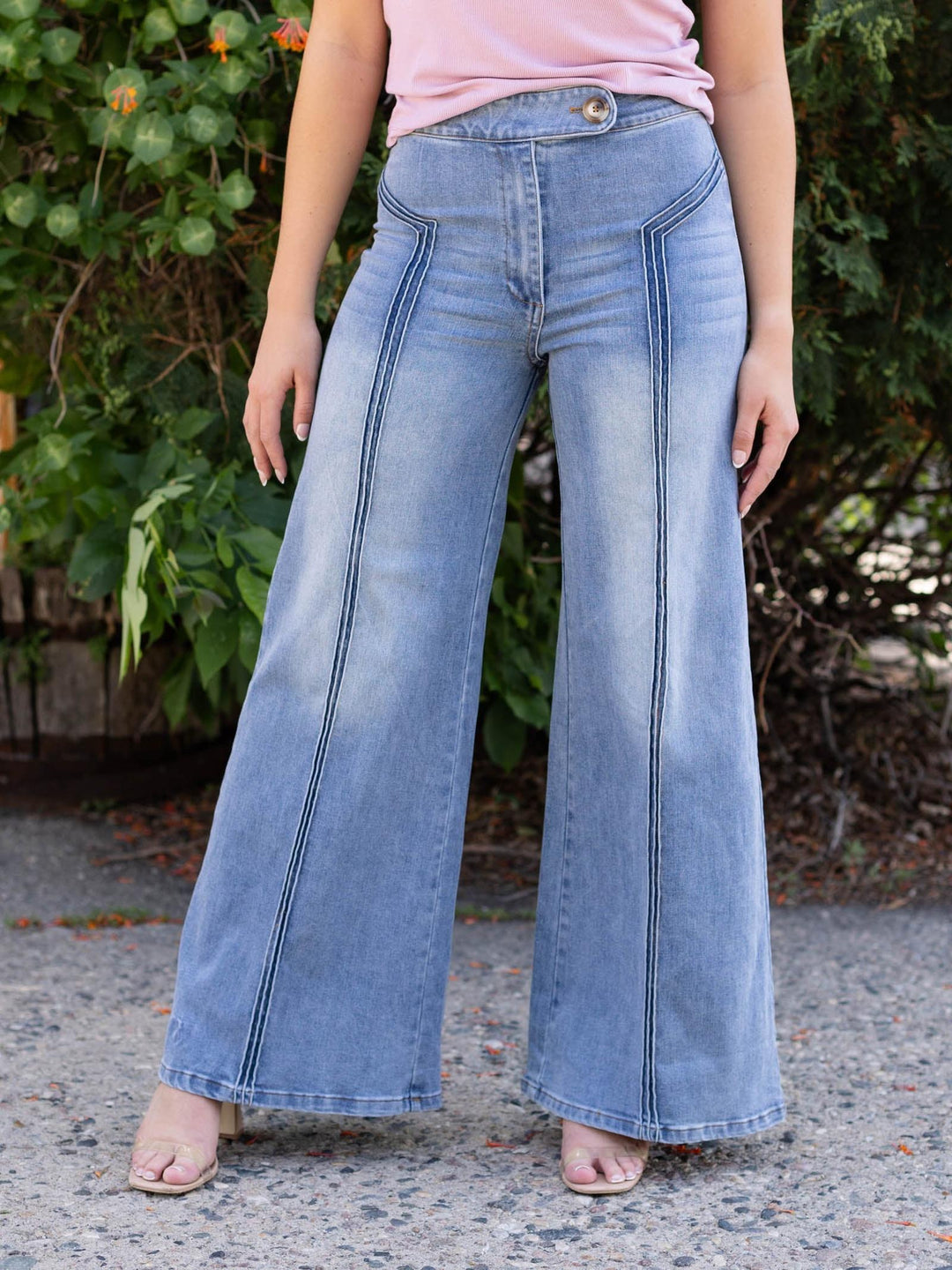 Light wash high-waisted wide-leg denim jeans with front seam detailing and a flap-over button waistband.