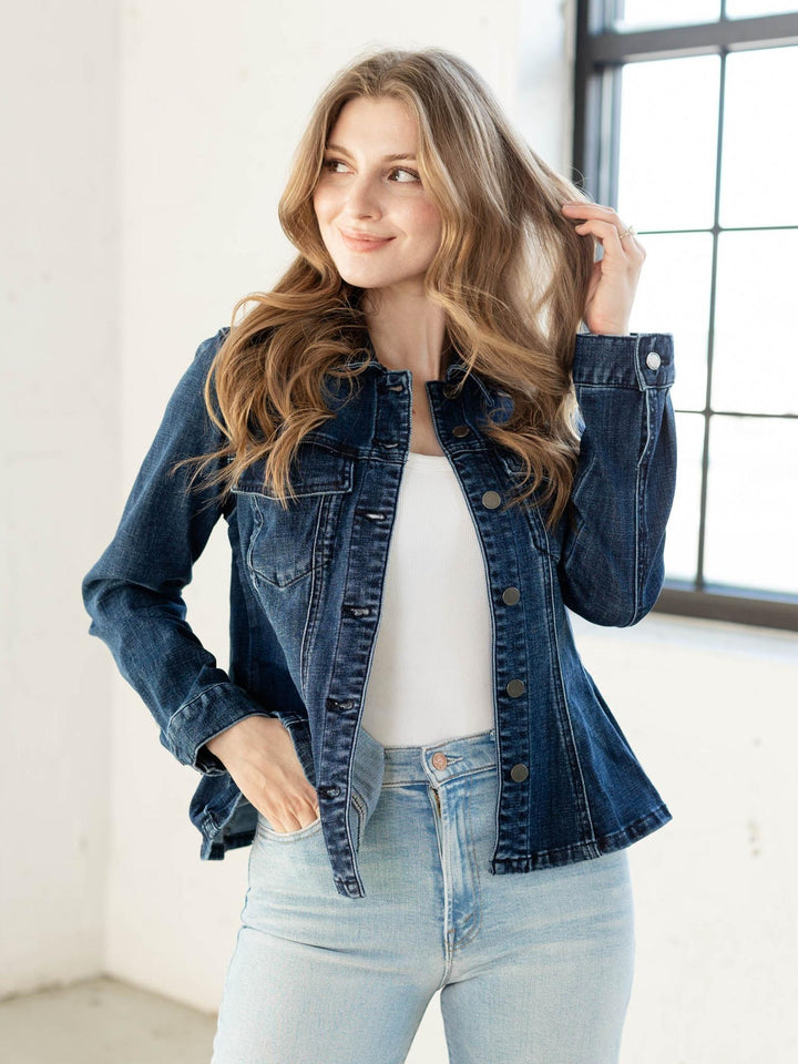 Woman wearing a denim jacket and light blue jeans indoors.