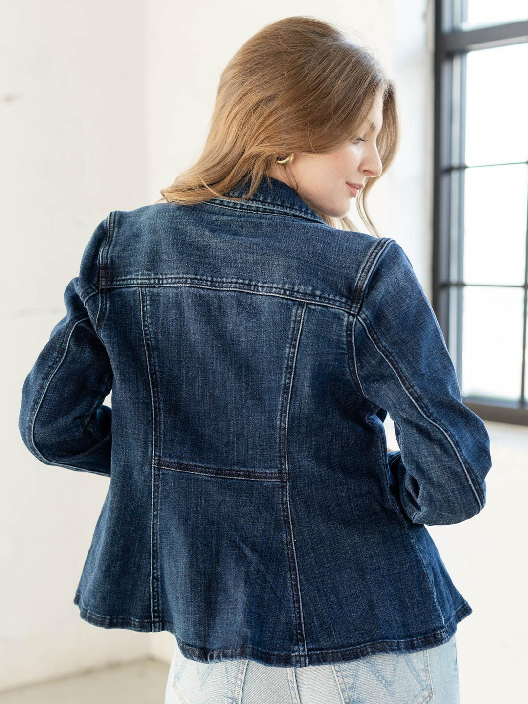 Woman wearing a blue denim jacket in a bright room.