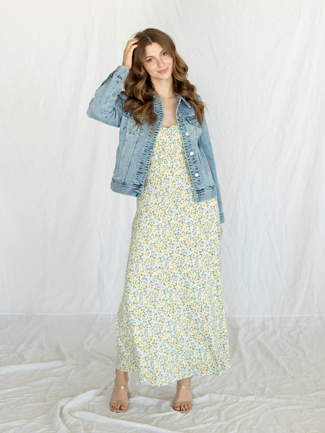 Woman wearing a floral dress and denim jacket on a white background