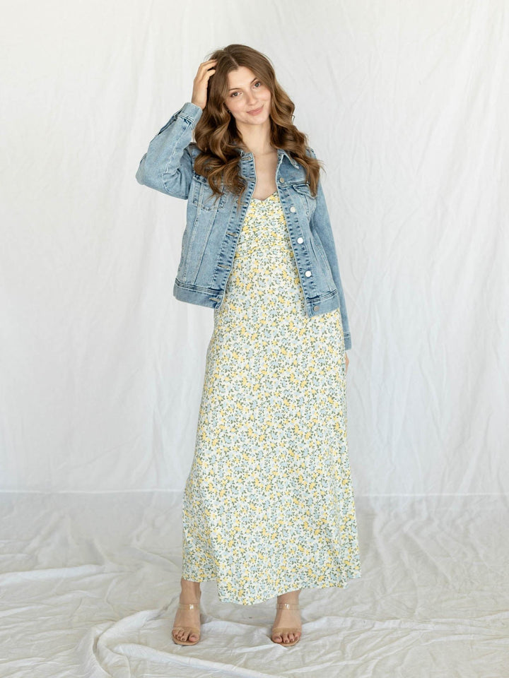 Woman wearing a floral dress and denim jacket on a white background