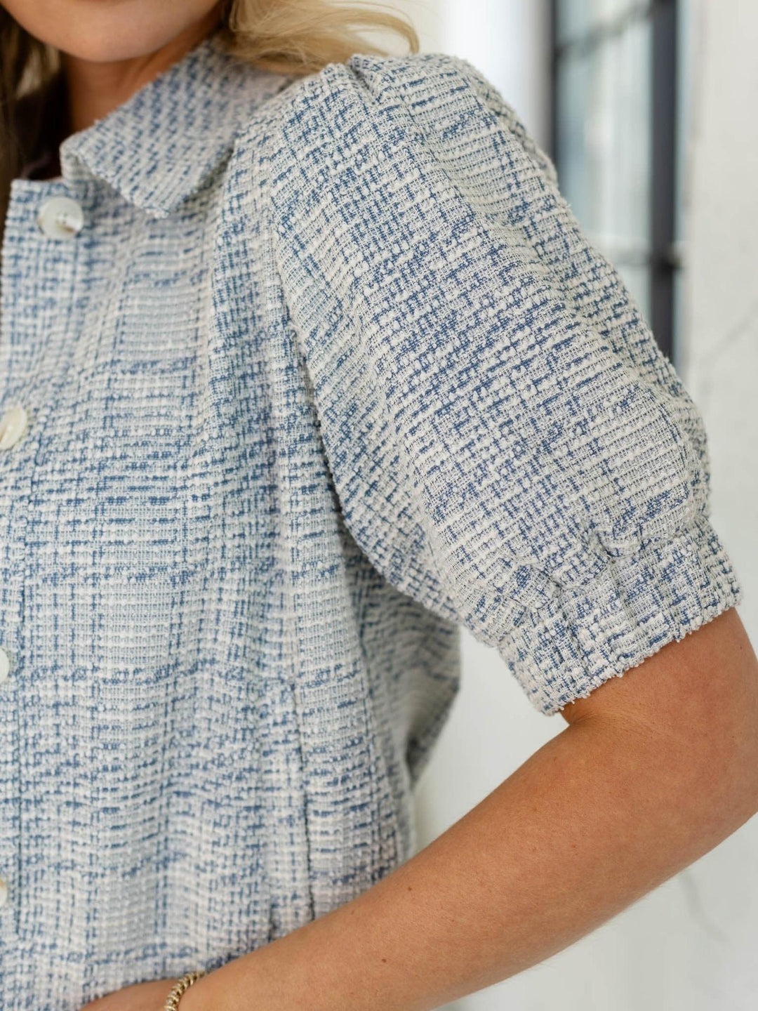 Close-up of a person wearing a textured blue and white shirt with a blurred background
