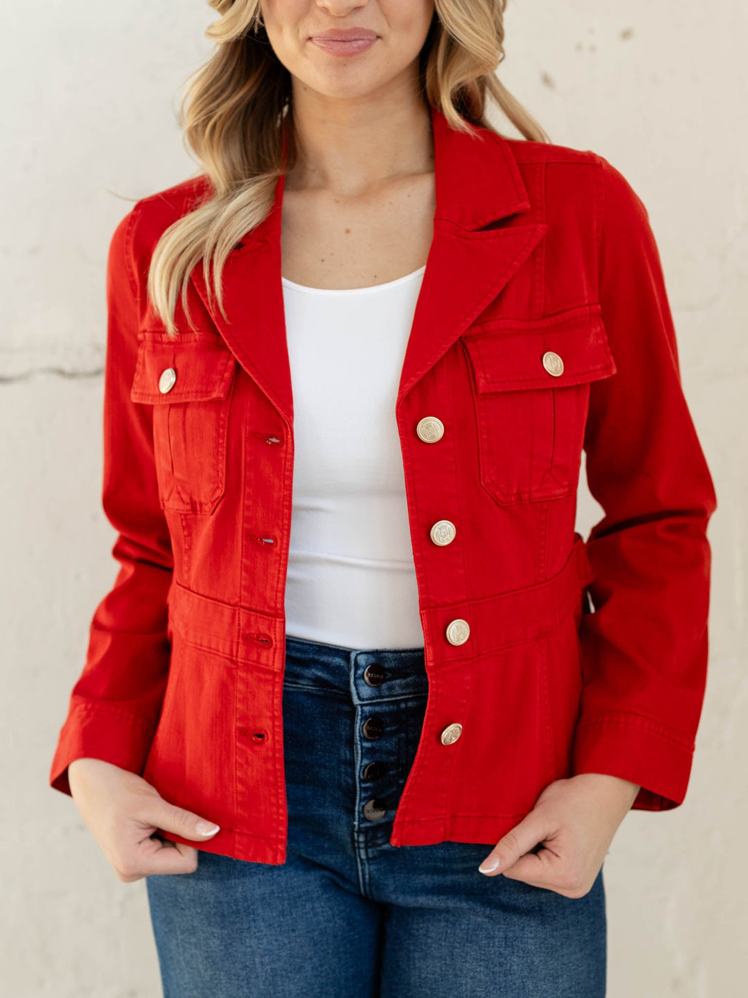 Person wearing a red jacket with white buttons on a plain background