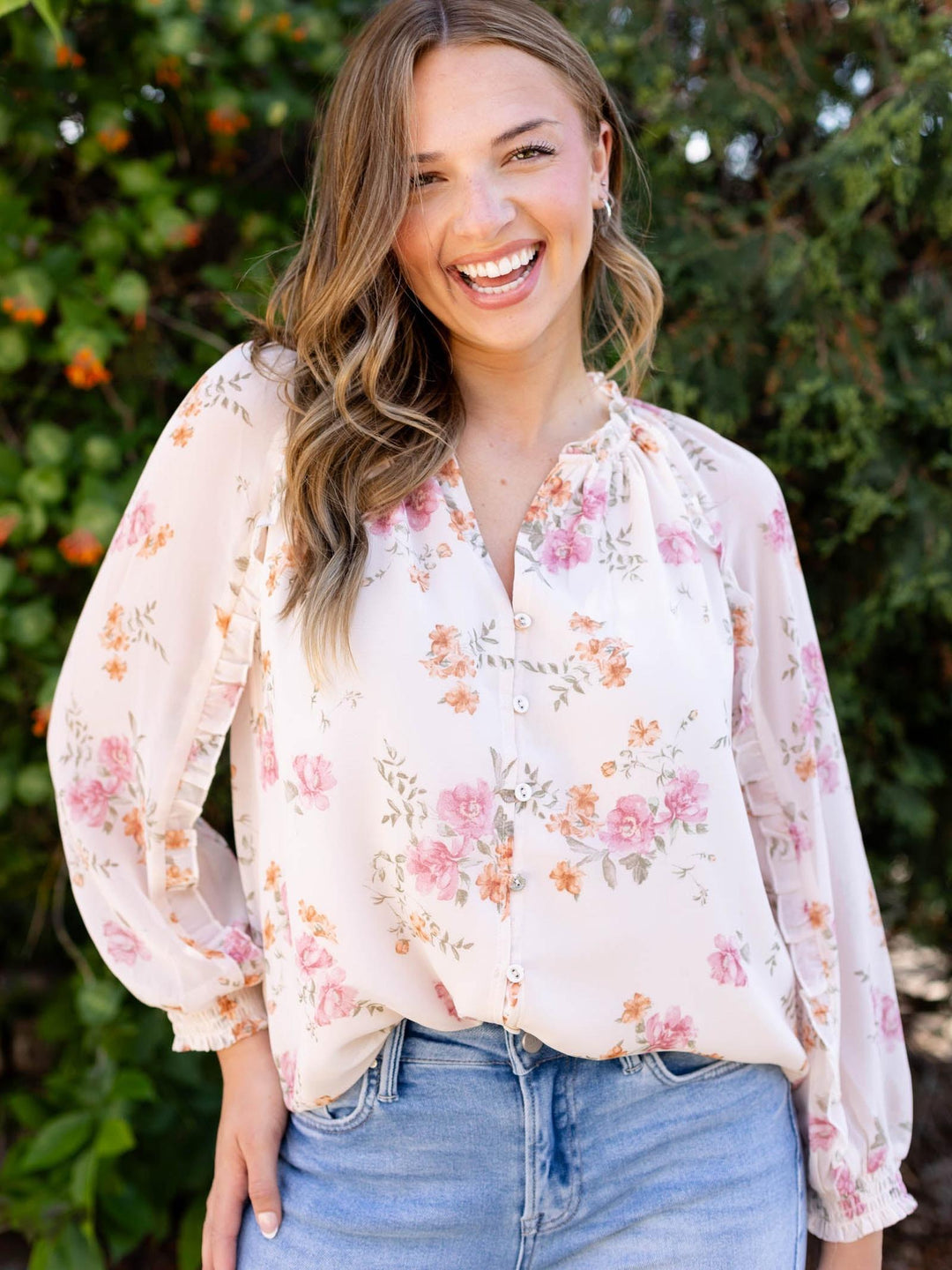Lovestitch Natural/Dusty Rose floral ruffle button blouse with v-neck, worn by a smiling model.