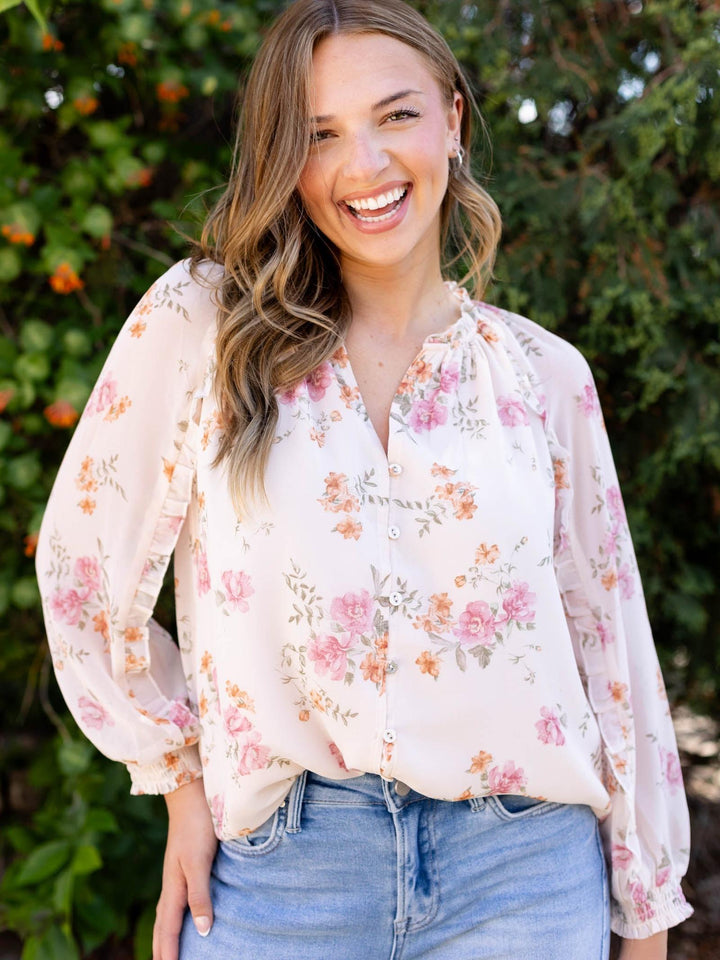 Lovestitch Natural/Dusty Rose floral ruffle button blouse with v-neck, worn by a smiling model.