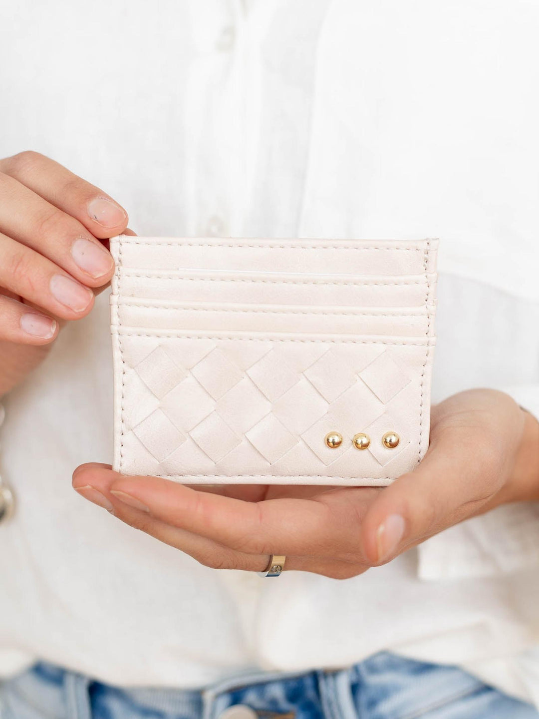 Person holding a quilted beige wallet with gold accents against a white background